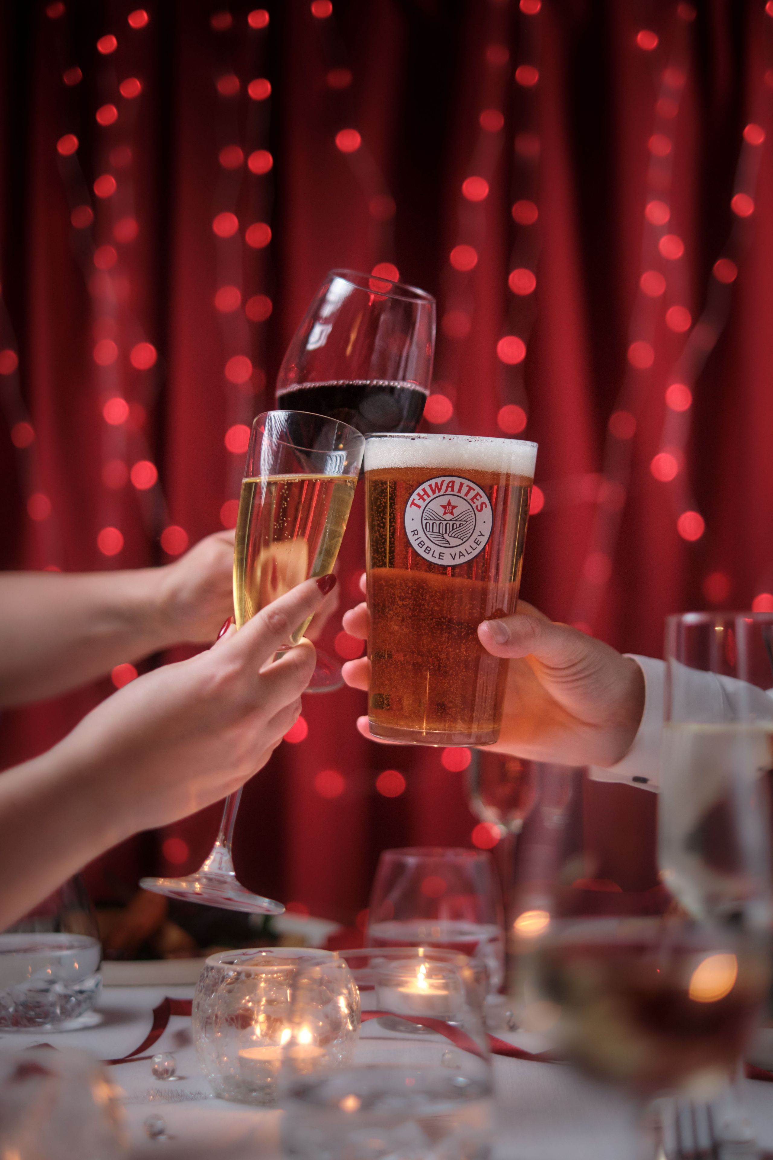 glasses cheersing, red wine, prosecco and thwaites ale