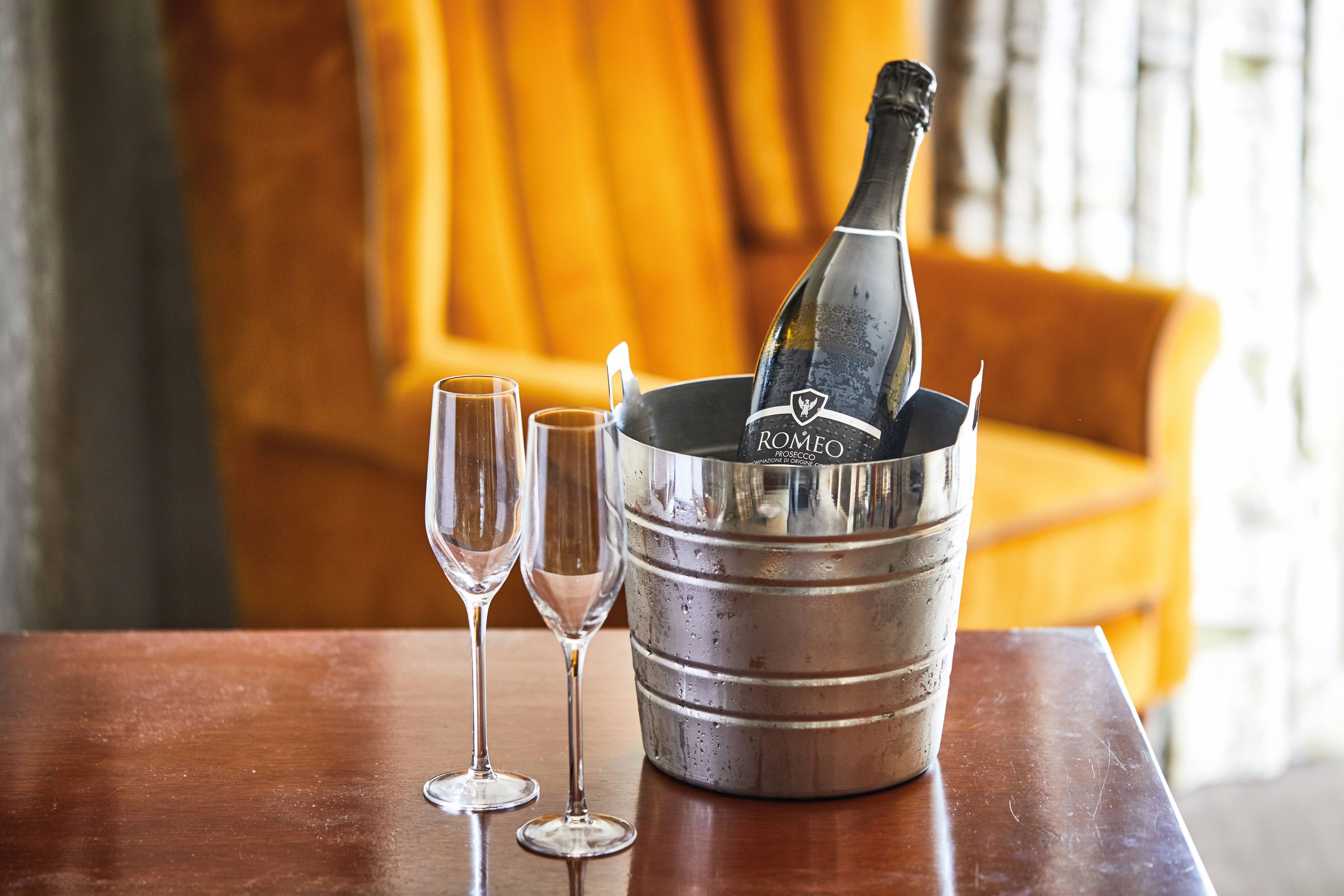 bottle of prosecco in an ice bucket with two prosecco glasses